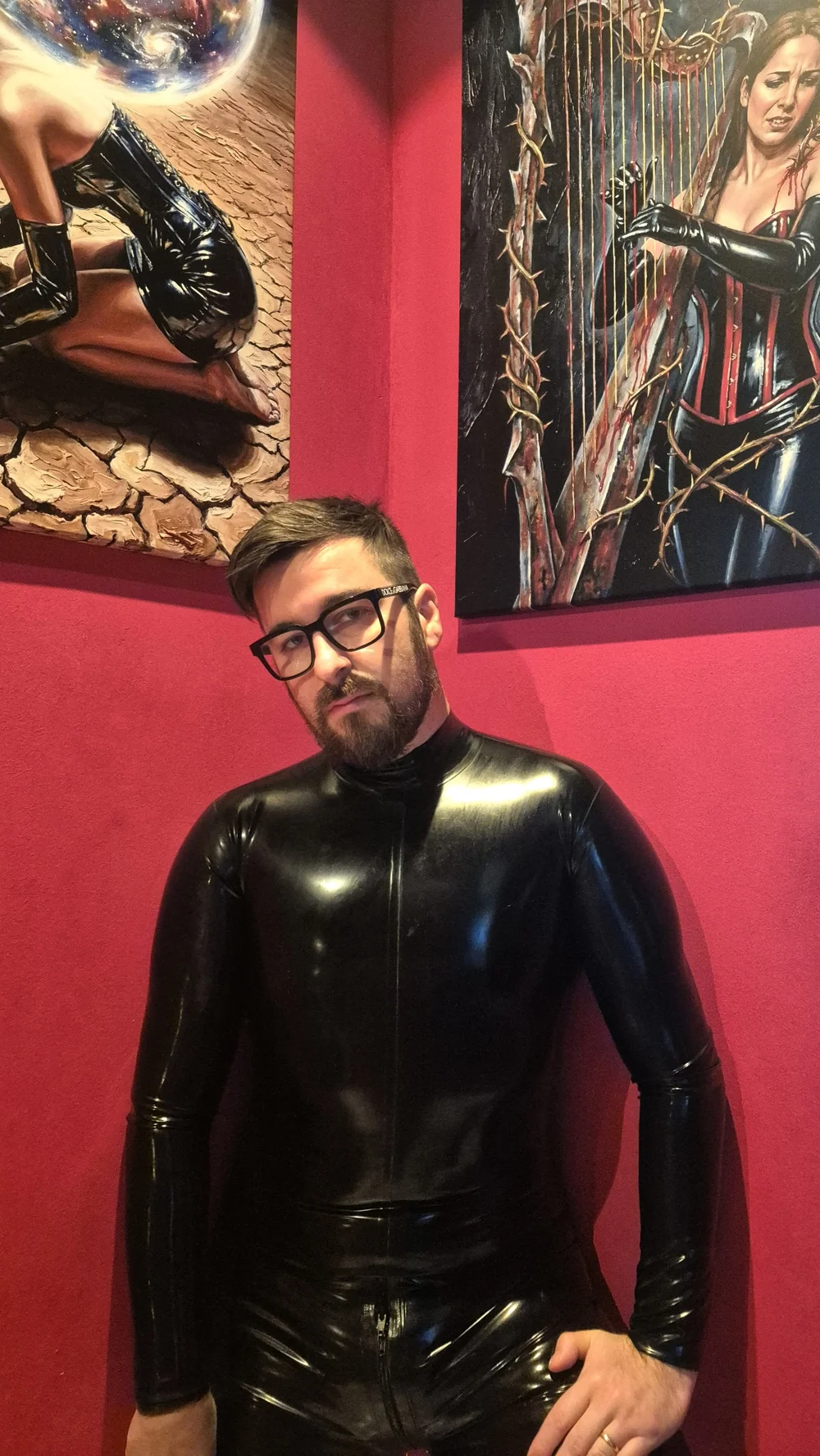 Lorenzo “Liam Dreams” Mureddu standing beside his paintings against a red wall